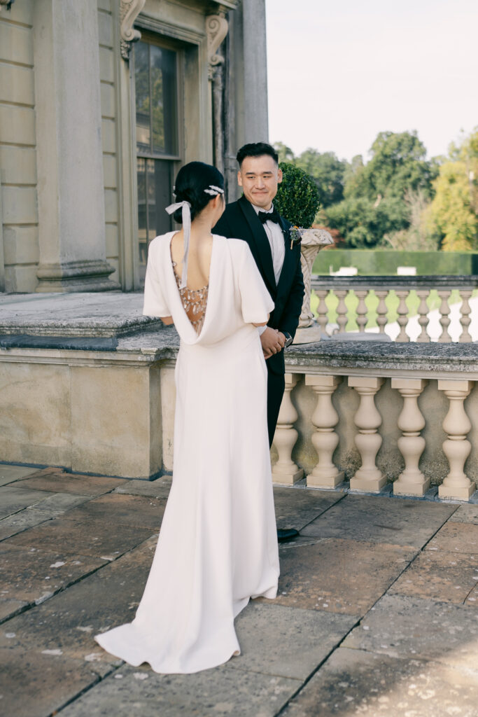 first look with bride in elegant high-neck wedding dress with open back