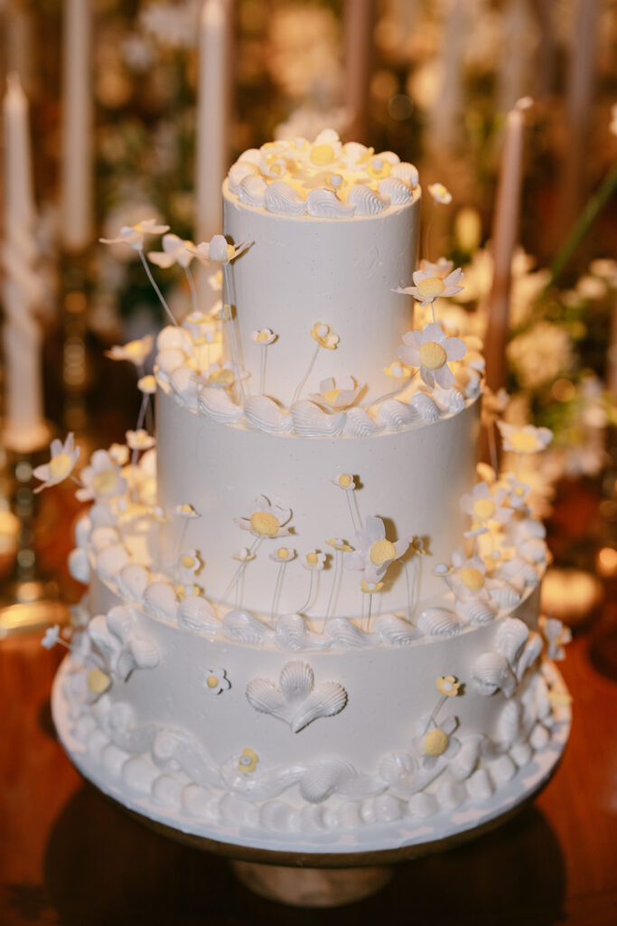 Editorial photo of a three layer wedding cake with frosting and flowers