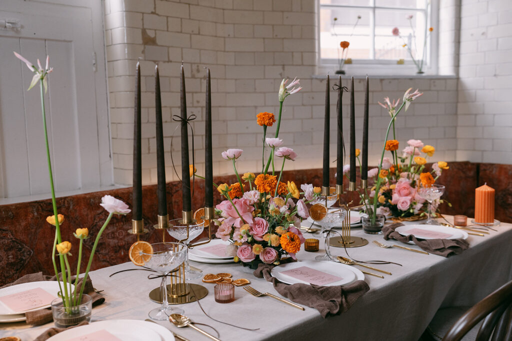 Wedding dinner party table with long tall black candles and colorful floral arrangements