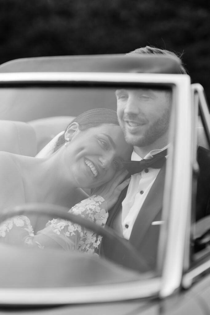 Newlyweds smiling sitting inside a car