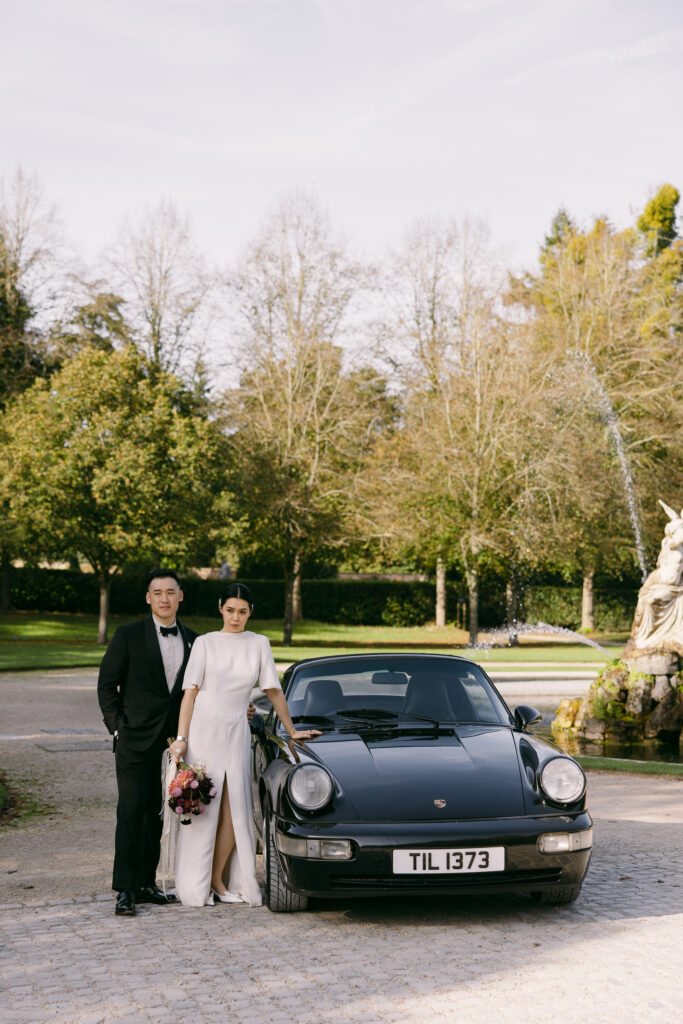 Bride and groom posing with a car