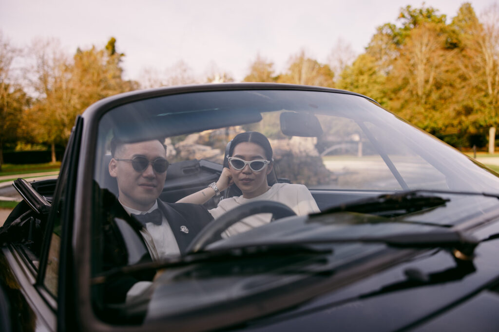 Bride and groom posing in a car for their wedding portrait photo
